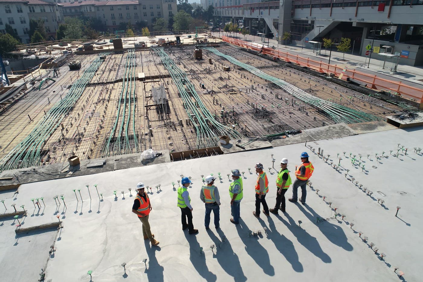 Equipo técnico con cascos y chalecos observando una obra desde una terraza
