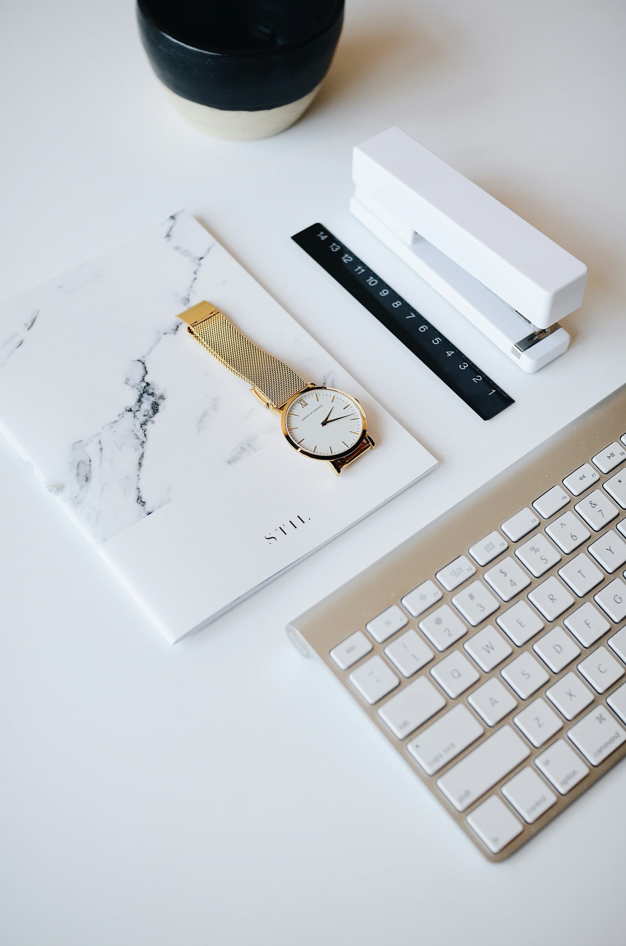 Escritorio blanco con reloj, libreta y teclado
